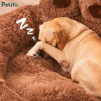 A golden retriever dozing off with its paw over its face inside a plush brown paw bed.