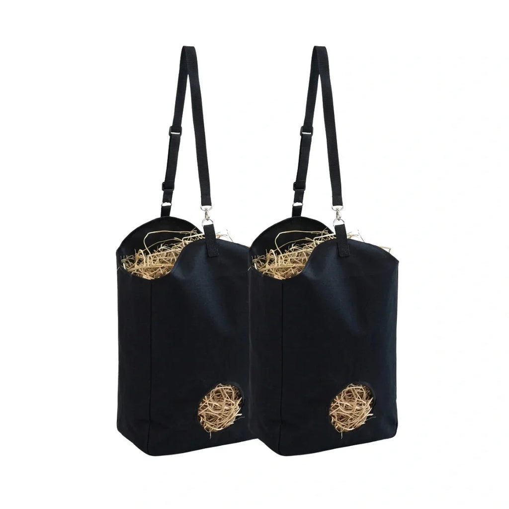 Two black hanging hay feeder bags filled with dry straw on a white background.