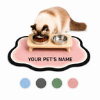 Fluffy cat eating from stainless steel bowls set on a customizable pink cloud-shaped pet feeding mat displayed with four color swatches.