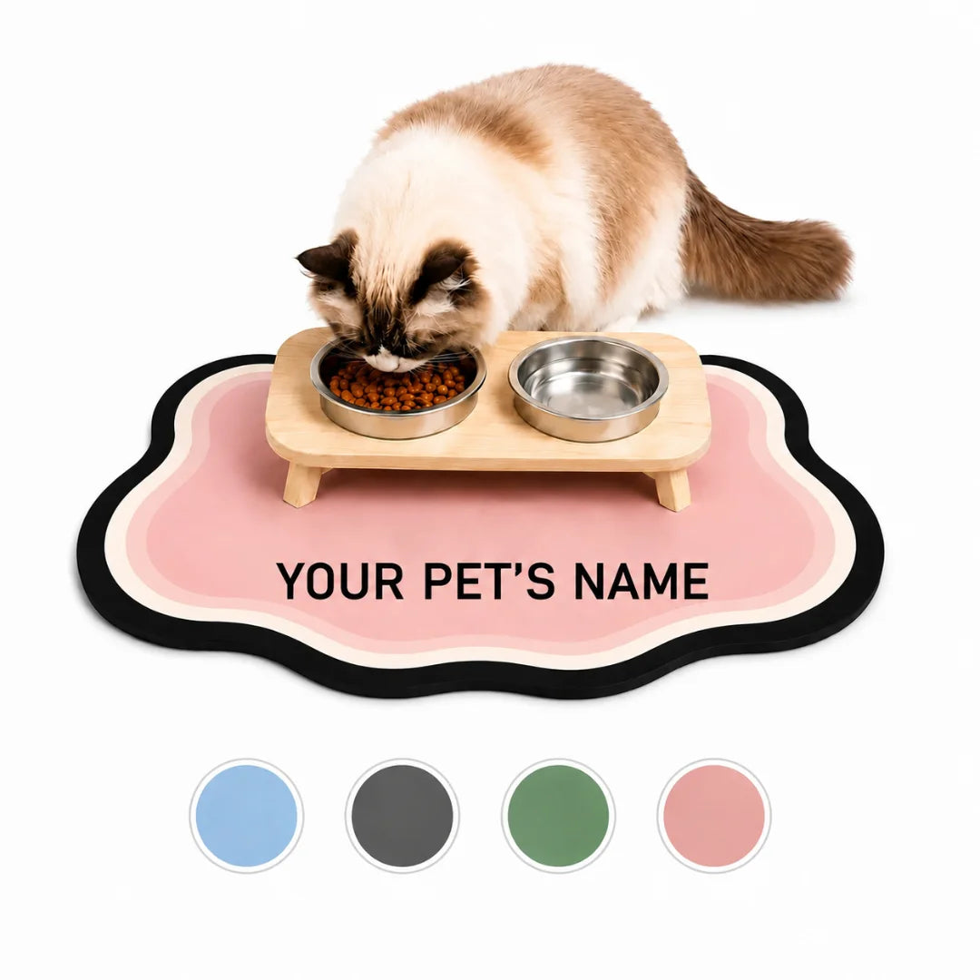 Fluffy cat eating from stainless steel bowls set on a customizable pink cloud-shaped pet feeding mat displayed with four color swatches.