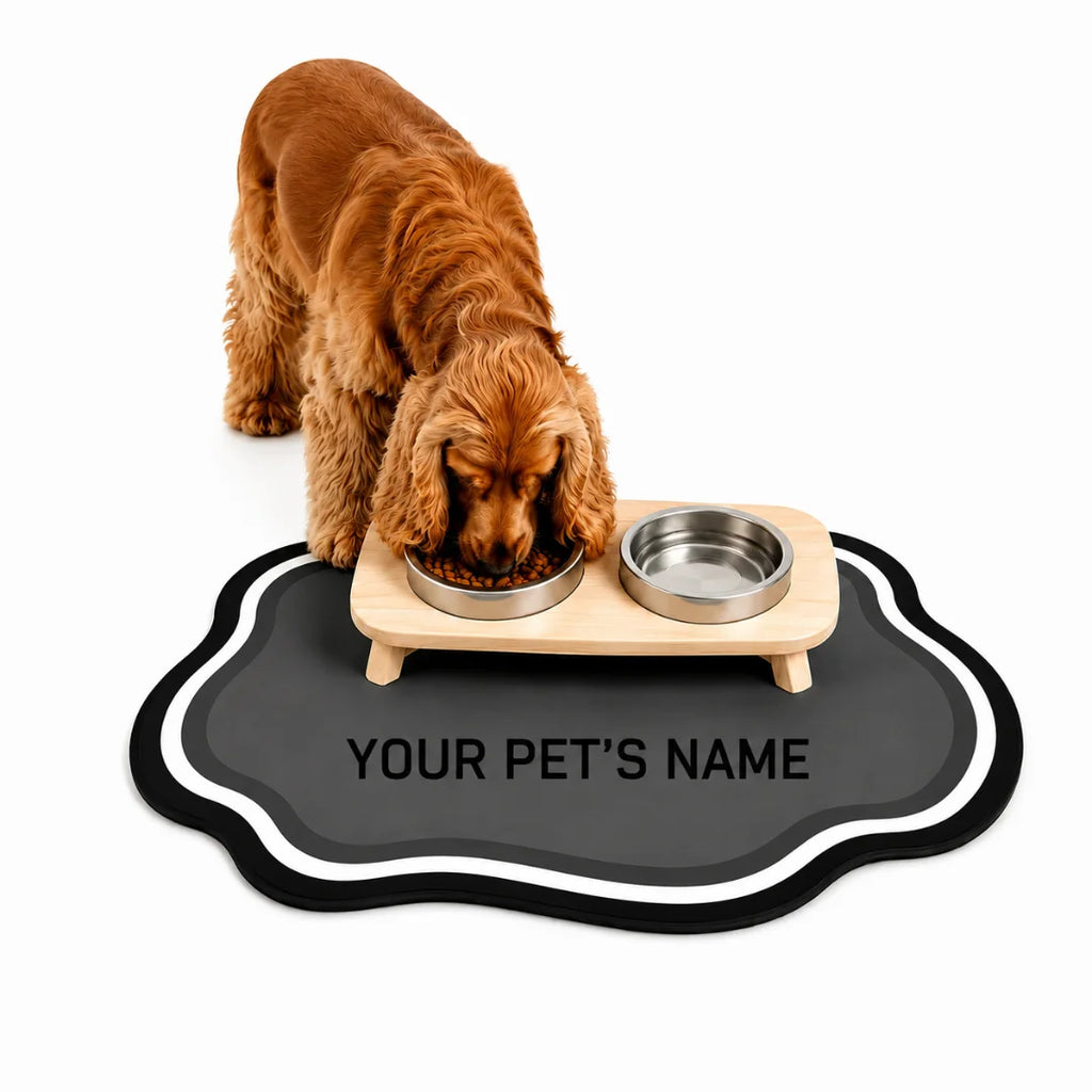 Cute cocker spaniel eating dry food from a raised wooden feeder set on a personalized gray cloud pet mat against a white background.