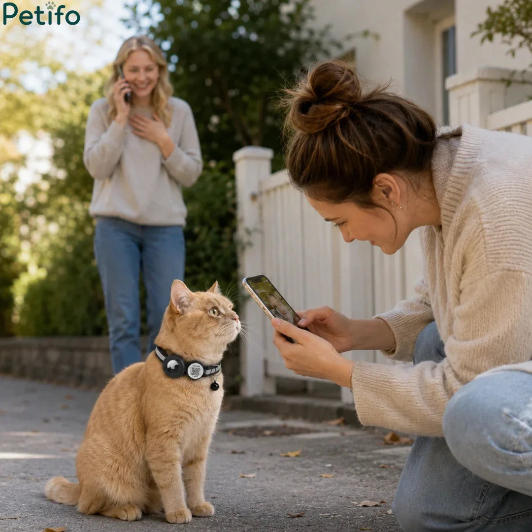 Lifestyle scene showing a woman smiling while scanning her ginger cat's smart safety collar with her smartphone outdoors.